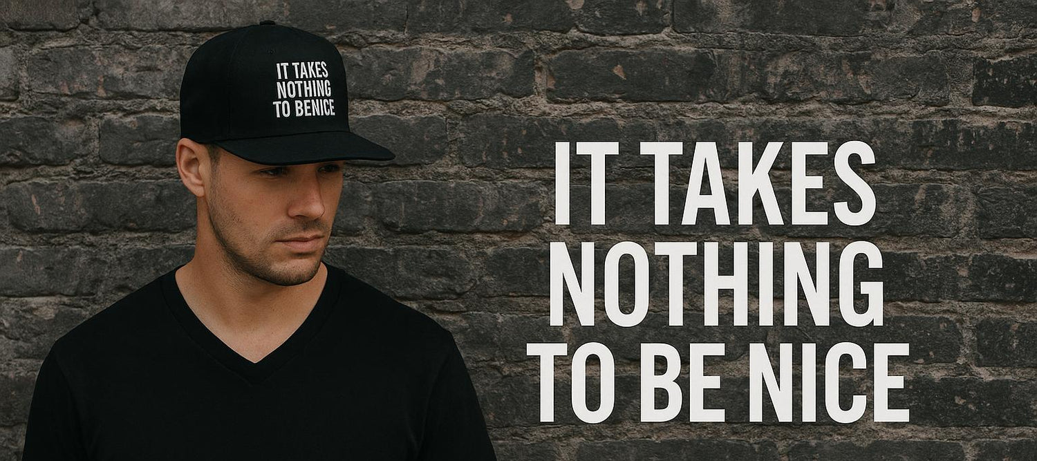 Man wearing a black cap and t-shirt with text against a brick wall, promoting 'It Takes Nothing to Be Nice' collection.